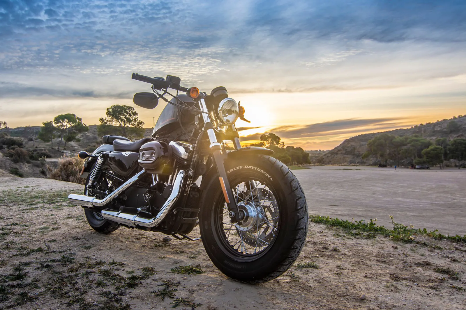 Motorcycle parked on an open road at sunset